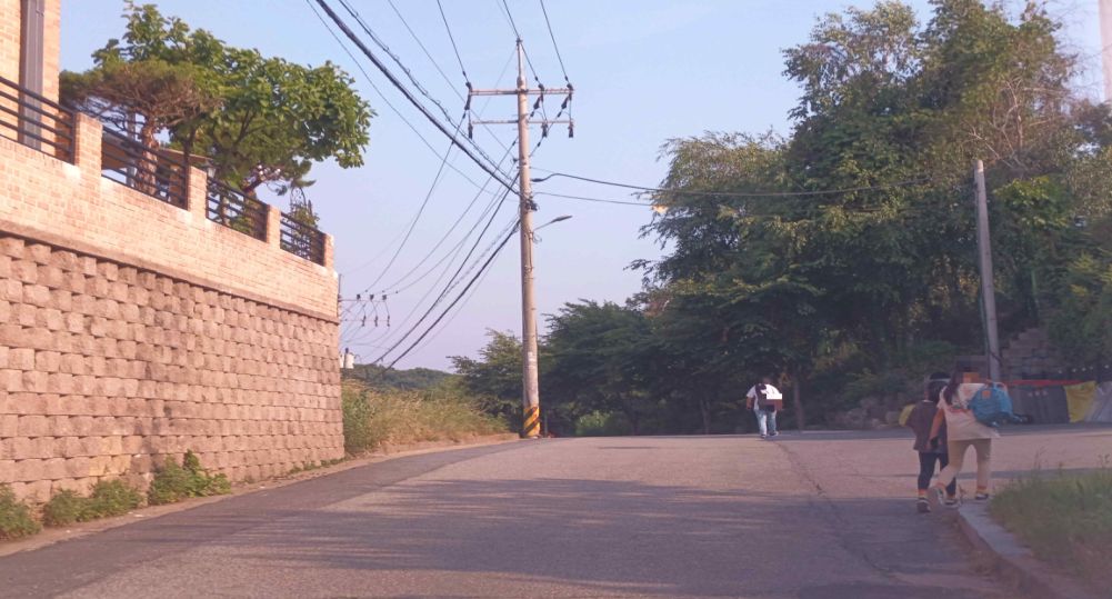 Đường nhỏ dốc lên trong khu dân cư, không có vỉa hè · Giao lộ hình chữ “ㅏ” có ngõ bên phải