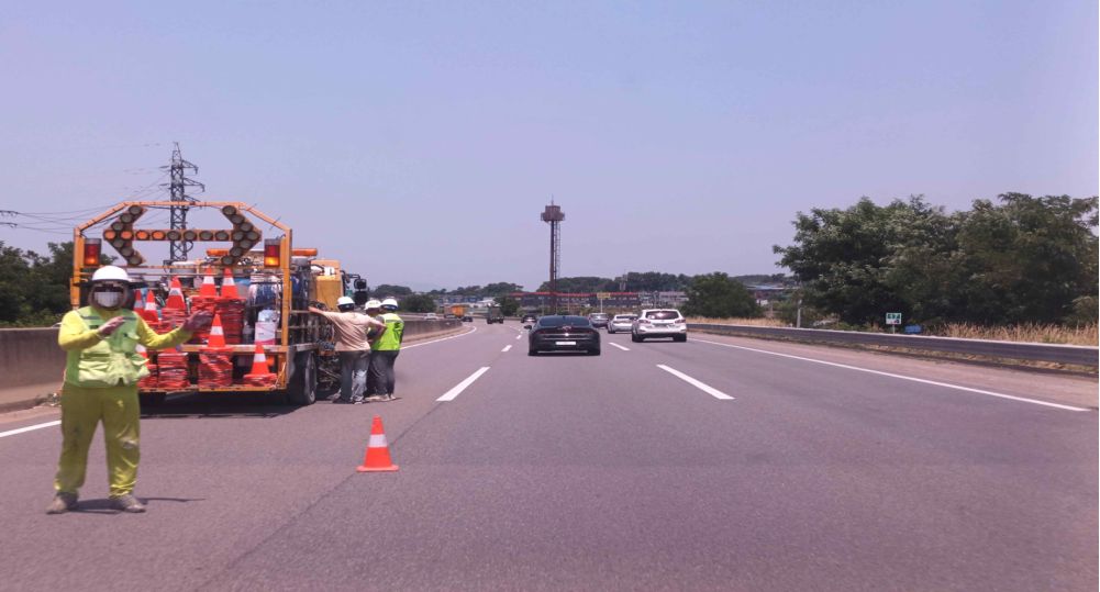 Expressway with three lanes in each direction · Construction guide vehicle stopped in lane 1 · Traveling in lane 2