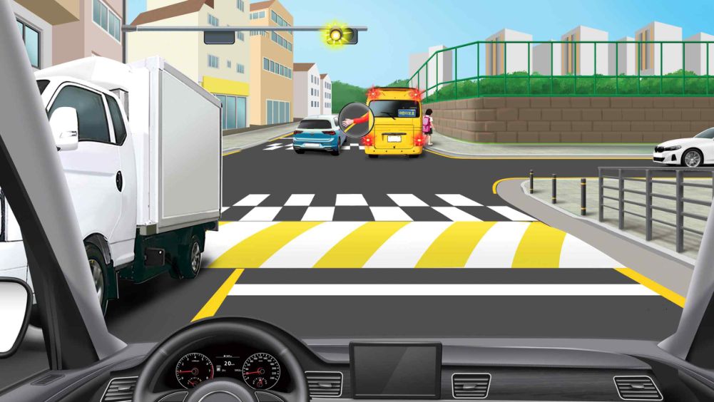 Children's school bus stopped at the corner of the intersection · School bus driver waving to the car behind