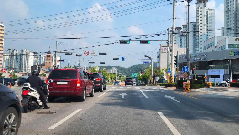 正在3车道道路的2车道上行驶 · 前方是有信号灯的交叉路口 · 有禁止掉头标志 · 前方信号灯上的安全标志表示“先直行后左转”的信号顺序