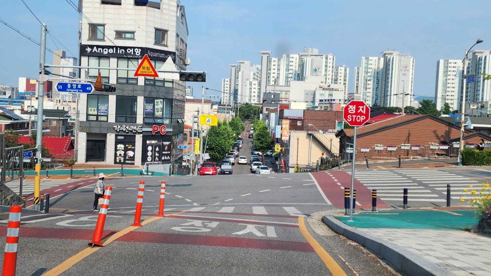 Tín hiệu đèn đỏ nhấp nháy đang hoạt động · Có người đi bộ đang băng qua vạch qua đường · Đường xuống dốc, ngã tư · Trên mặt đường có chữ "Dừng lại", bên phải có biển báo ghi "Dừng lại"