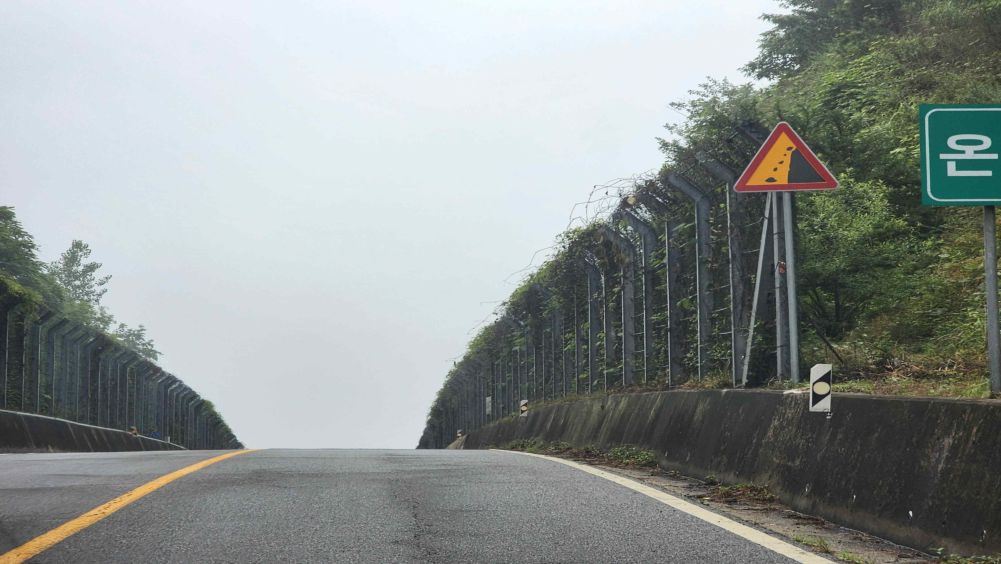 道路右侧有安全标志 · 坡顶道路上坡 · 因下雨路面湿滑的状态