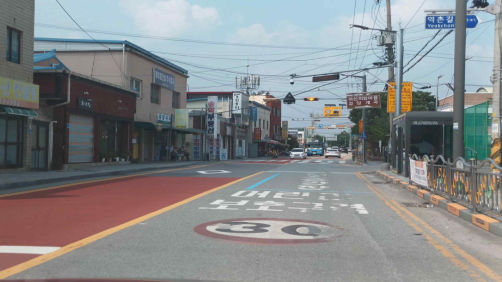 In front of a bus stop in a children's protection zone, one-way 1-lane road · Intersection with a flashing yellow light · People waiting for a bus at the bus stop ahead on the right