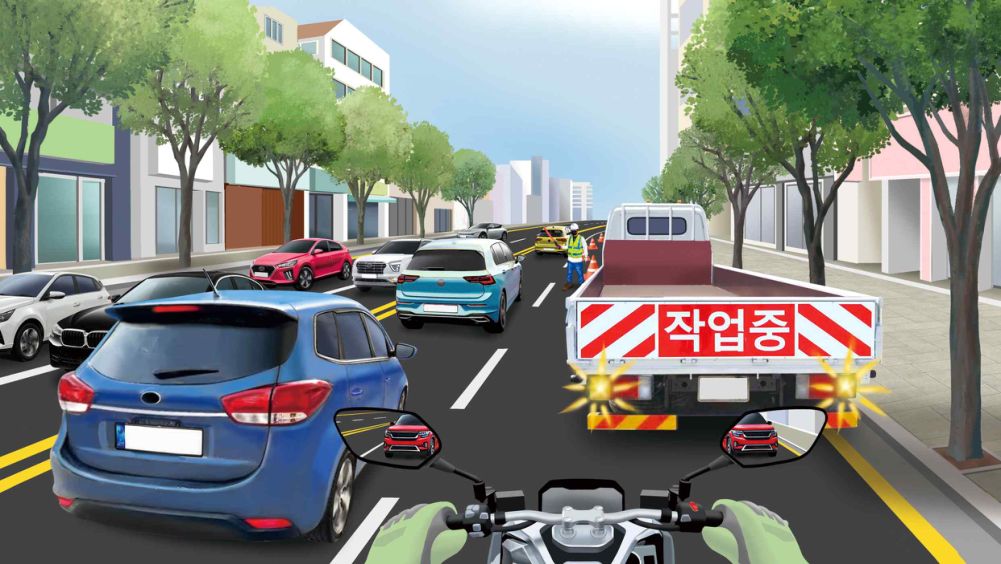 Riding in lane 2 on a road with two lanes each way · A construction vehicle stopped and working in lane 2 ahead · A red car following behind